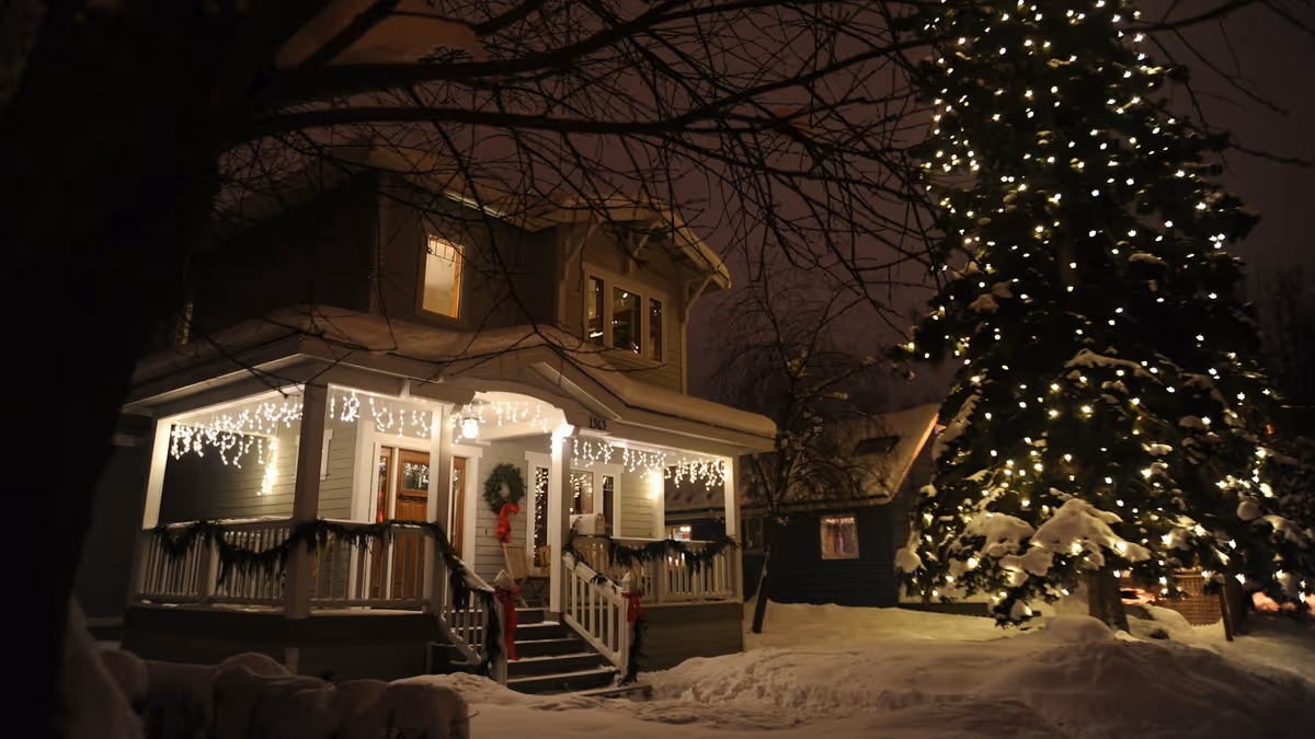 Casa con luces tipo cascada en el techo y árbol iluminado en una noche de invierno