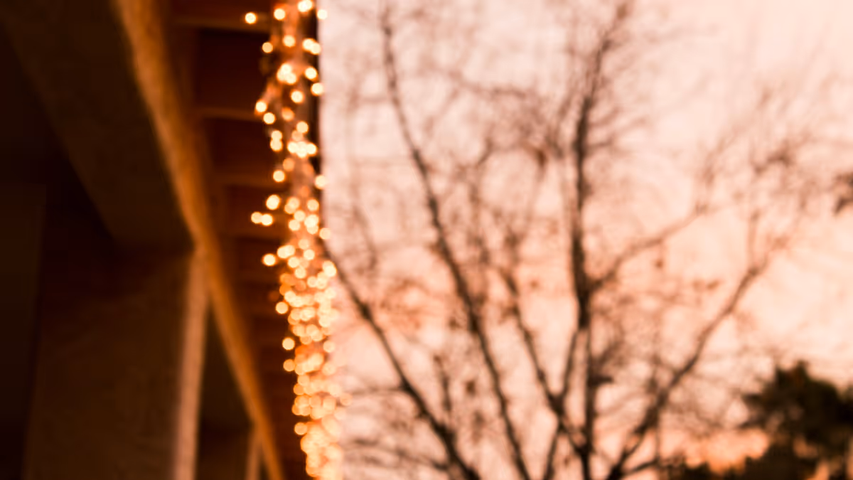 Hilera de luces cálidas colgando del borde de un techo al atardecer