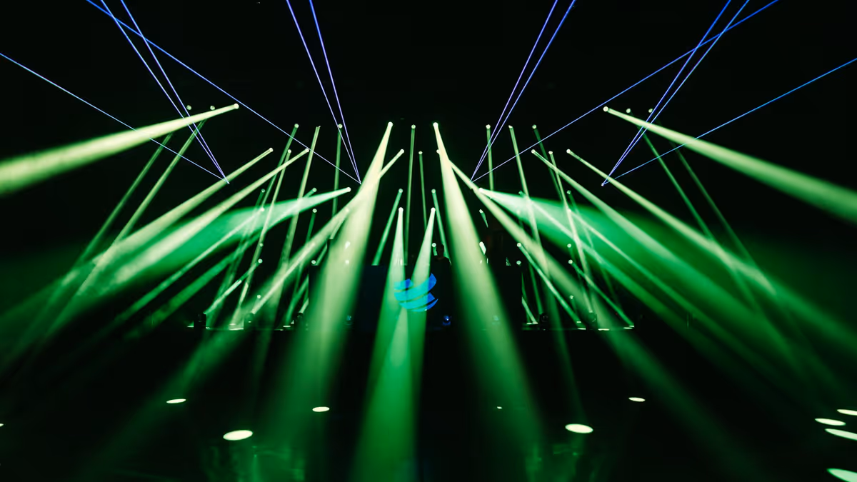 Abanico de haces verdes de luces robóticas sobre un escenario oscuro