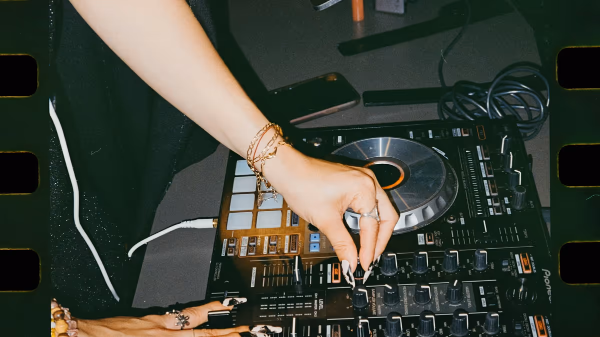Persona ajustando controles de mezcla junto a una computadora portátil