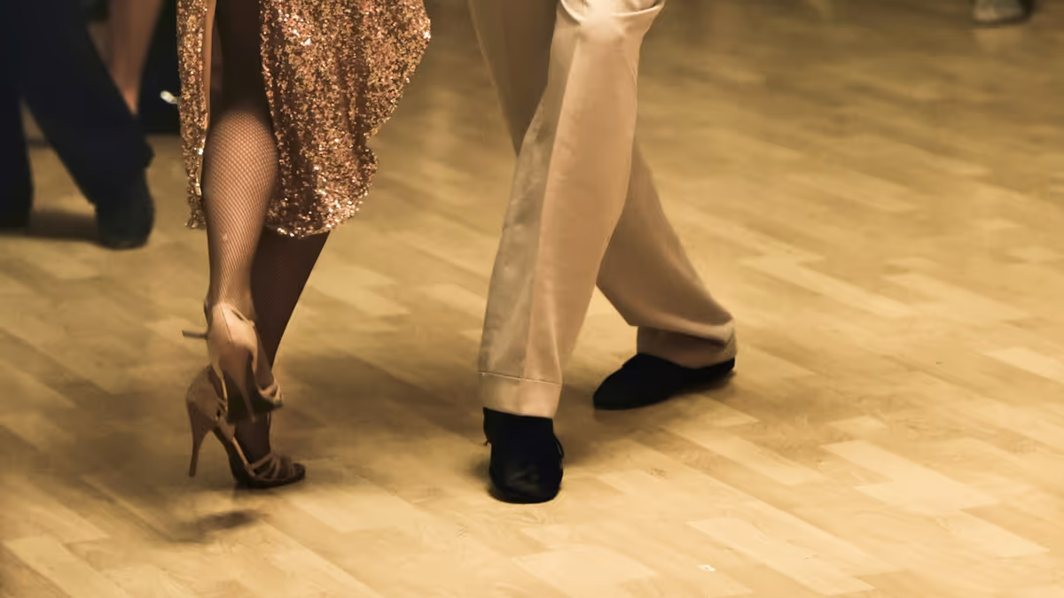 Pies de una pareja bailando sobre una pista de madera durante la fiesta