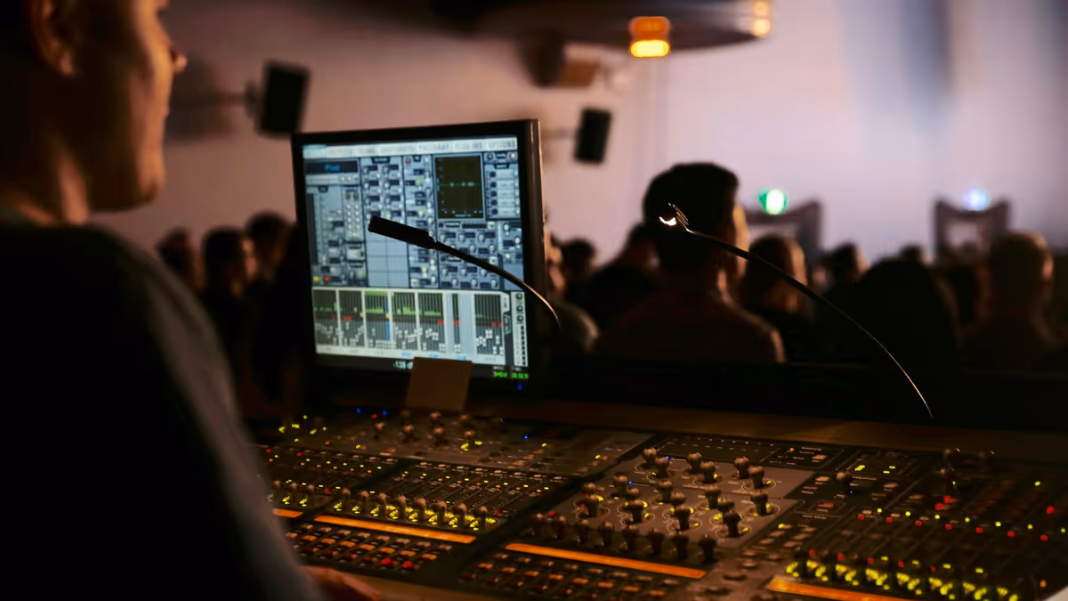 Técnico de audio frente a consola y asistentes desenfocados