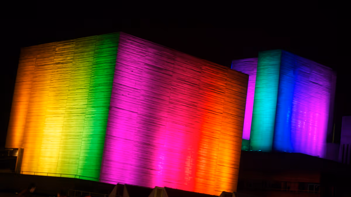 Muros rectangulares iluminados en amarillo rosa y verde durante la noche