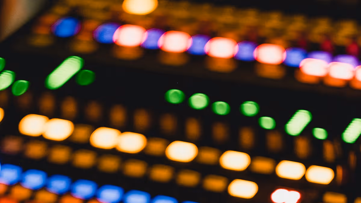 Primer plano de una consola de audio con botones iluminados en tonos cálidos