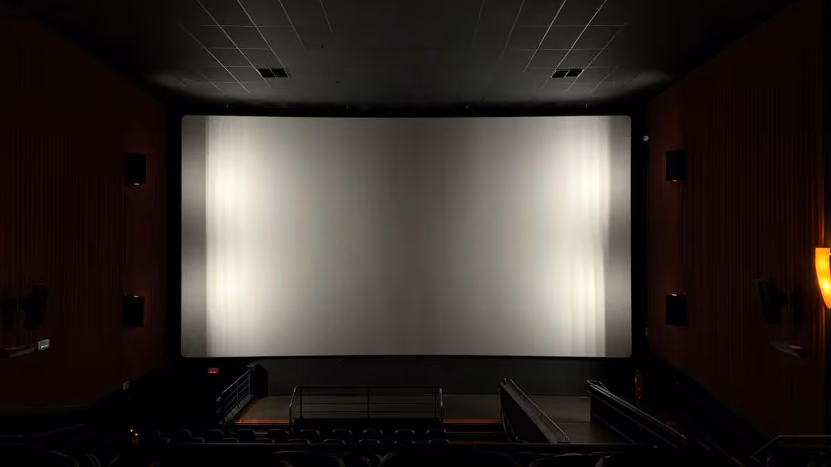 Pantalla de proyección blanca en una sala oscura con butacas
