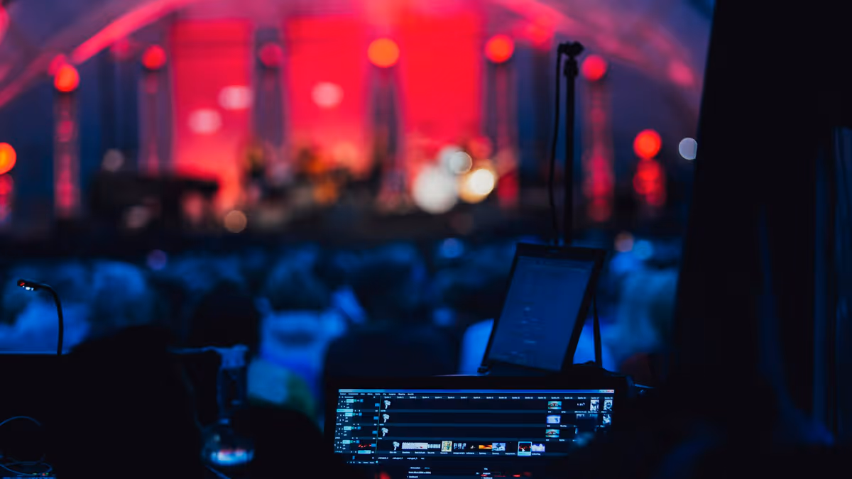 Escenario con computadora portátil y micrófono frente a una multitud
