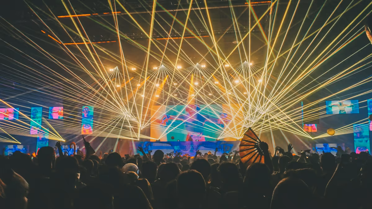 Personas reunidas cerca del escenario con iluminación beam y neblina