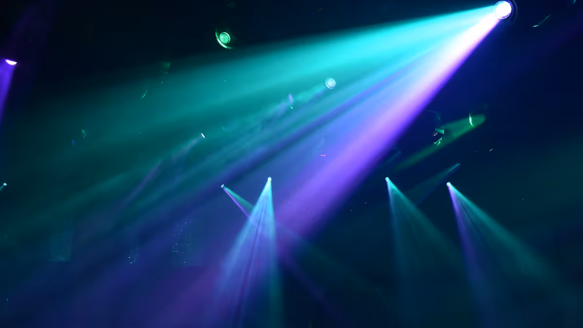 Focos verde azulado y morado cruzando atmósfera brumosa de discoteca
