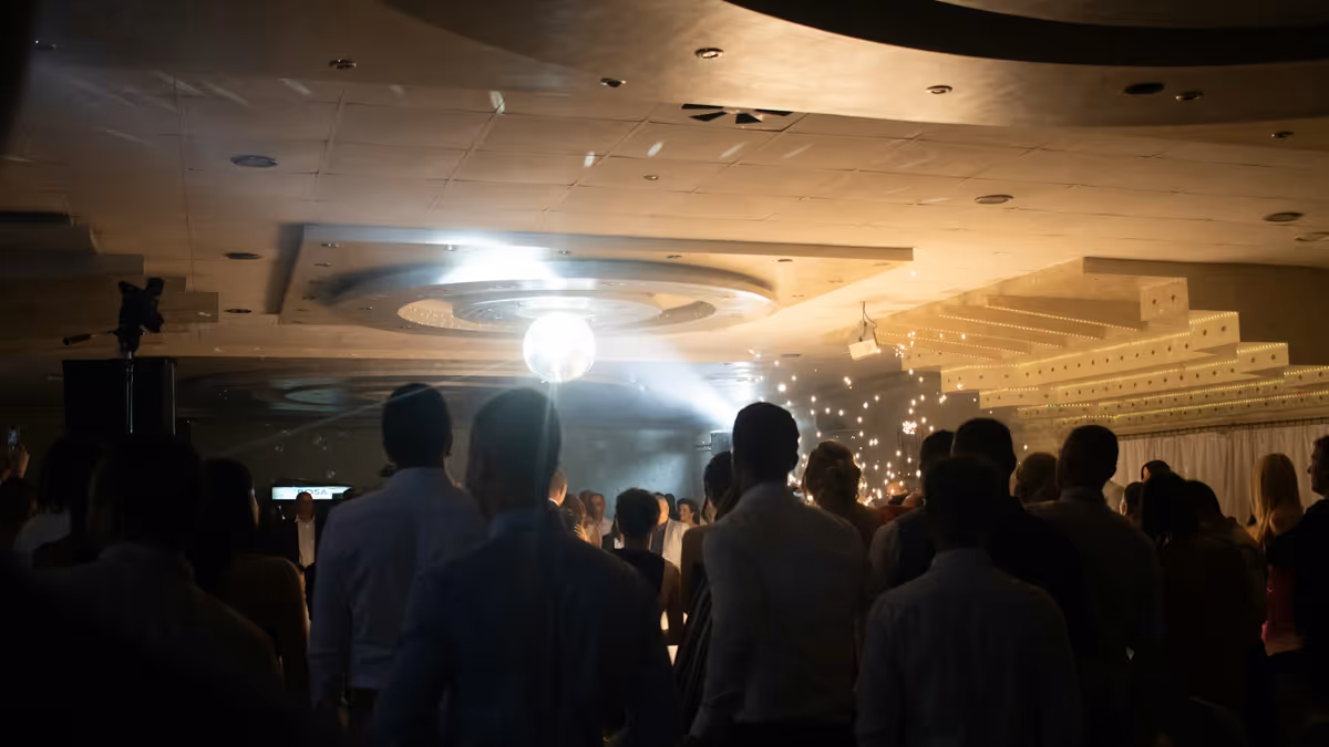 Invitados bailando bajo una bola disco y luces en un salón de eventos