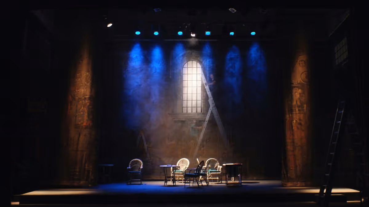 Escenario con mesas y sillas bajo focos azules y fondo pintado