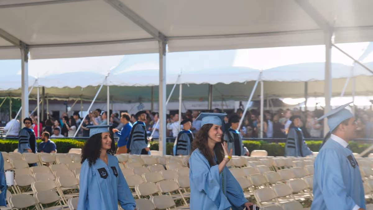 Graduados con túnicas azul claro caminan junto a filas de sillas