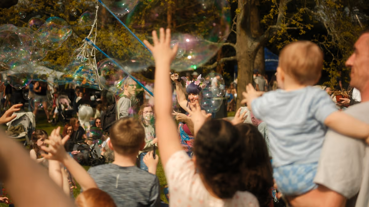 Niños alcanzando grandes burbujas durante un evento al aire libre