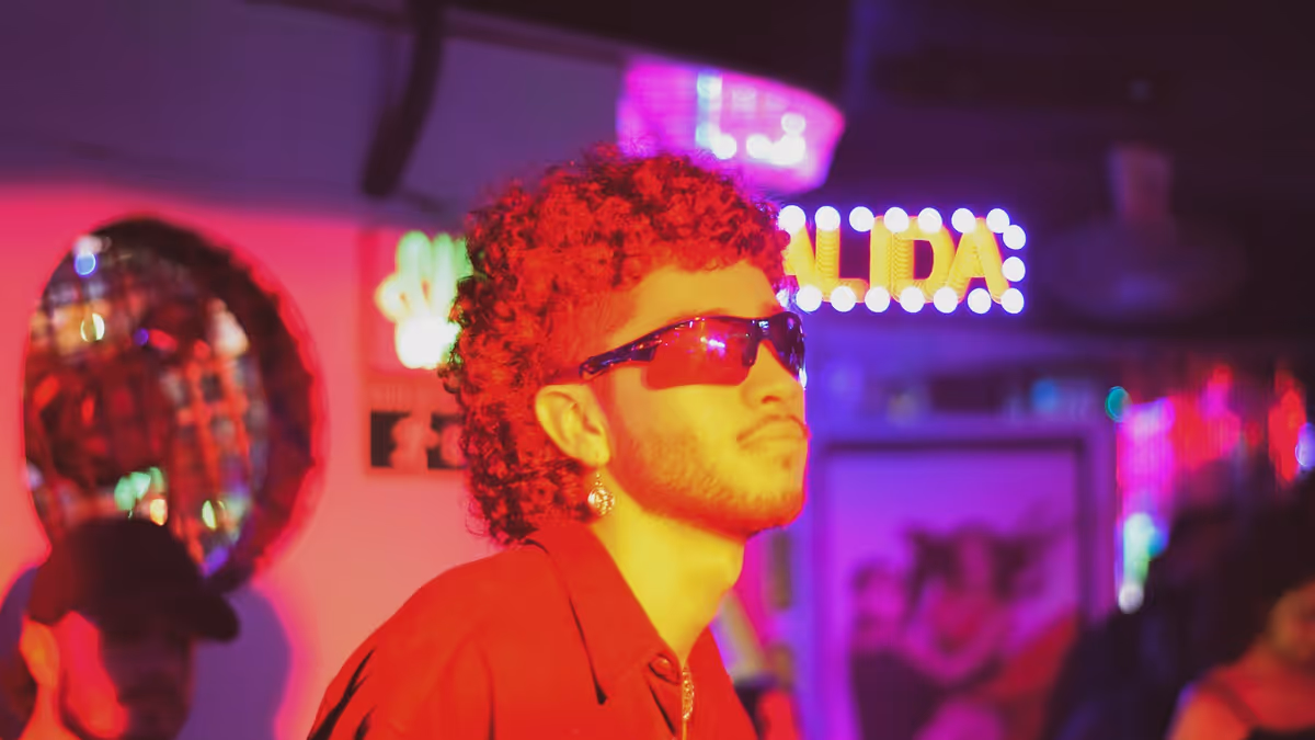 Hombre con gafas de sol en club oscuro iluminado