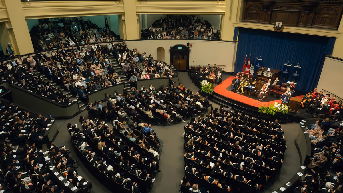 Público reunido en auditorio durante ceremonia de graduación iluminada