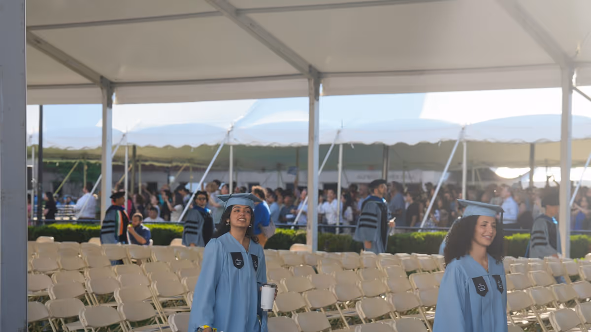 Dos graduados con túnicas azul claro junto a sillas para ceremonia