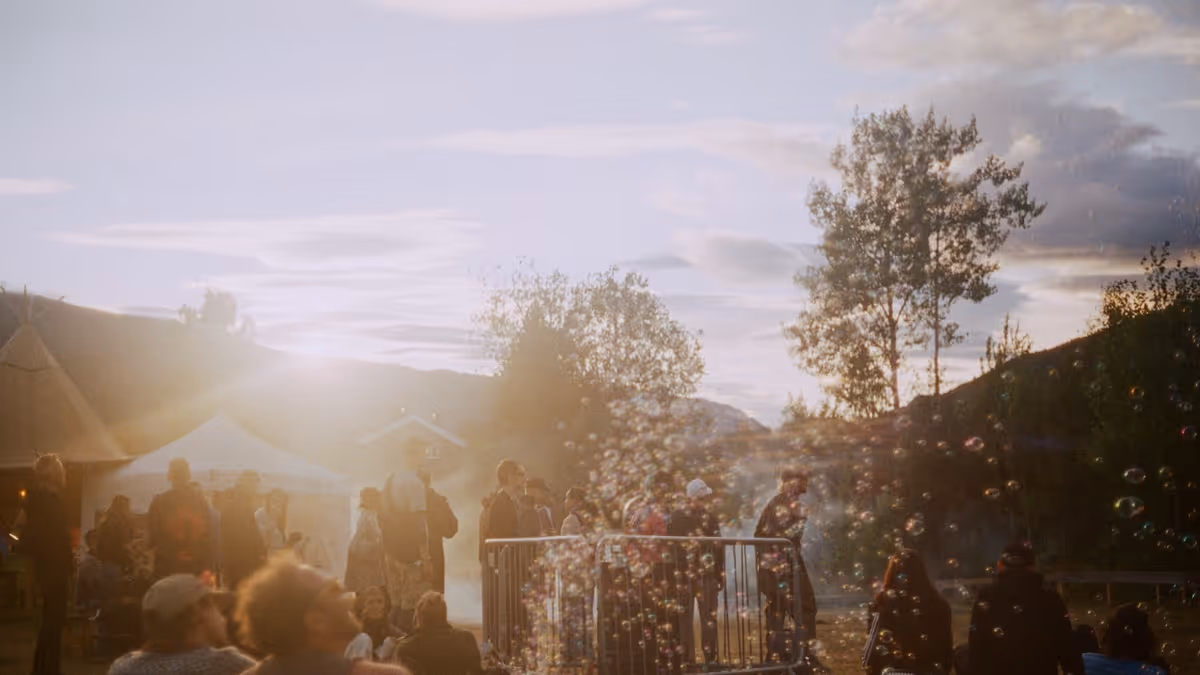 Personas en festival al aire libre con burbujas bajo luz dorada