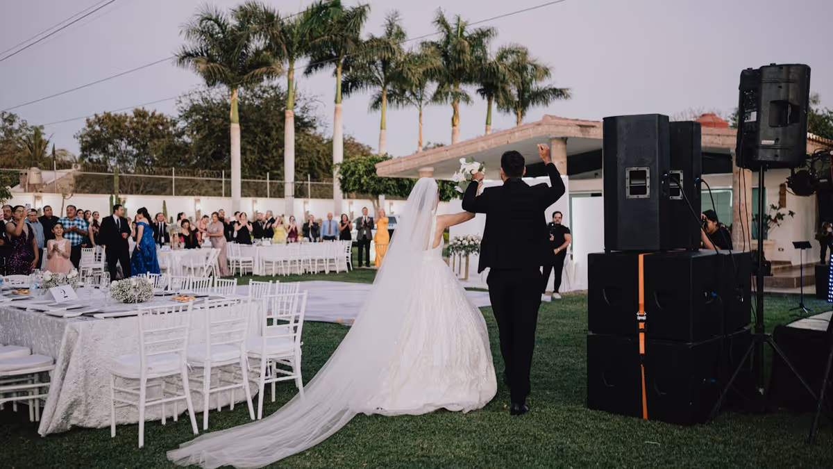 Recién casados caminan hacia la recepción mientras invitados los observan