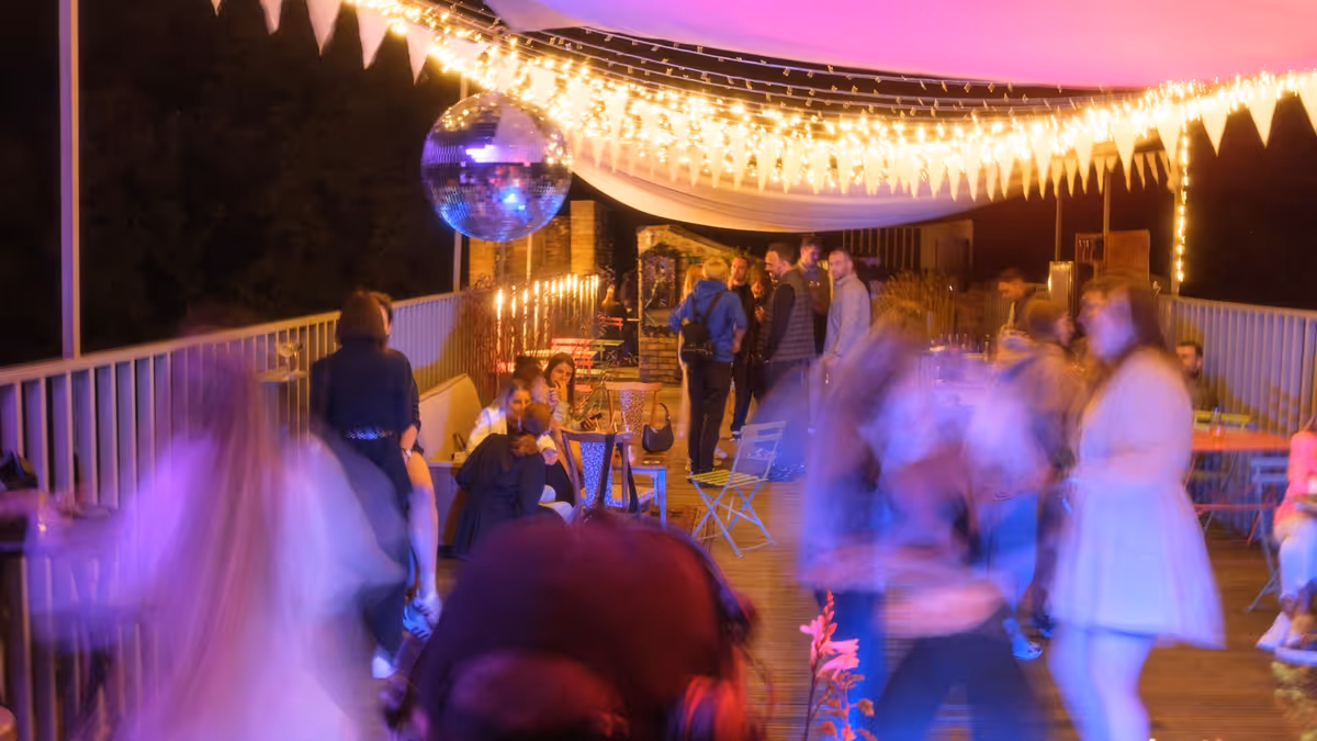 Personas bailando en terraza durante boda nocturna con iluminación ambiental