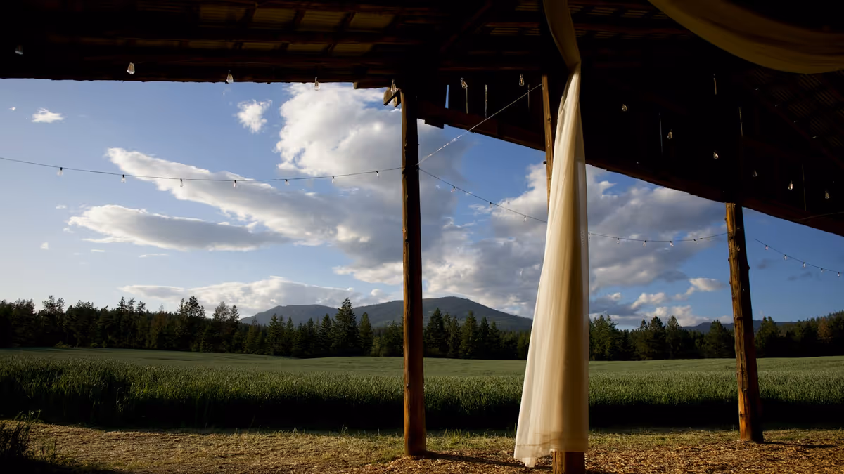 Interior de granero para boda con campo verde, árboles y montañas