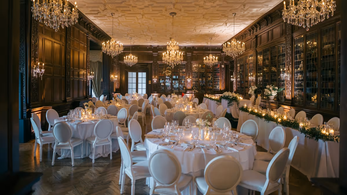 Salón de gala con candelabros y mesas blancas preparadas