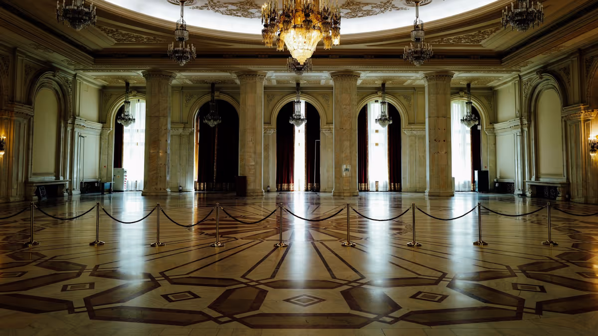 Gran salón con columnas de mármol, candelabros y suelo geométrico pulido