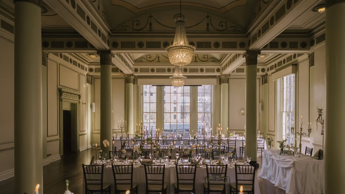 Salón elegante con mesas largas, candelabros y columnas iluminadas