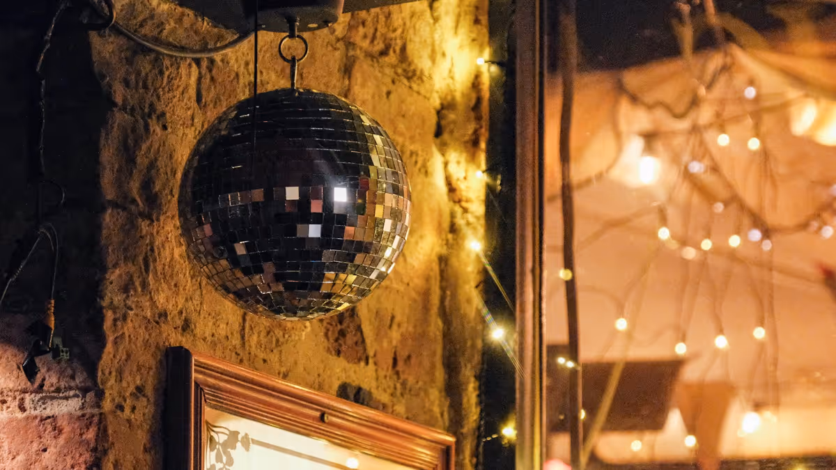 Bola de discoteca colgada frente a una pared rústica brillante
