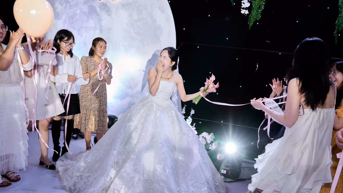 Novia riendo con vestido blanco y flores rodeada de invitados