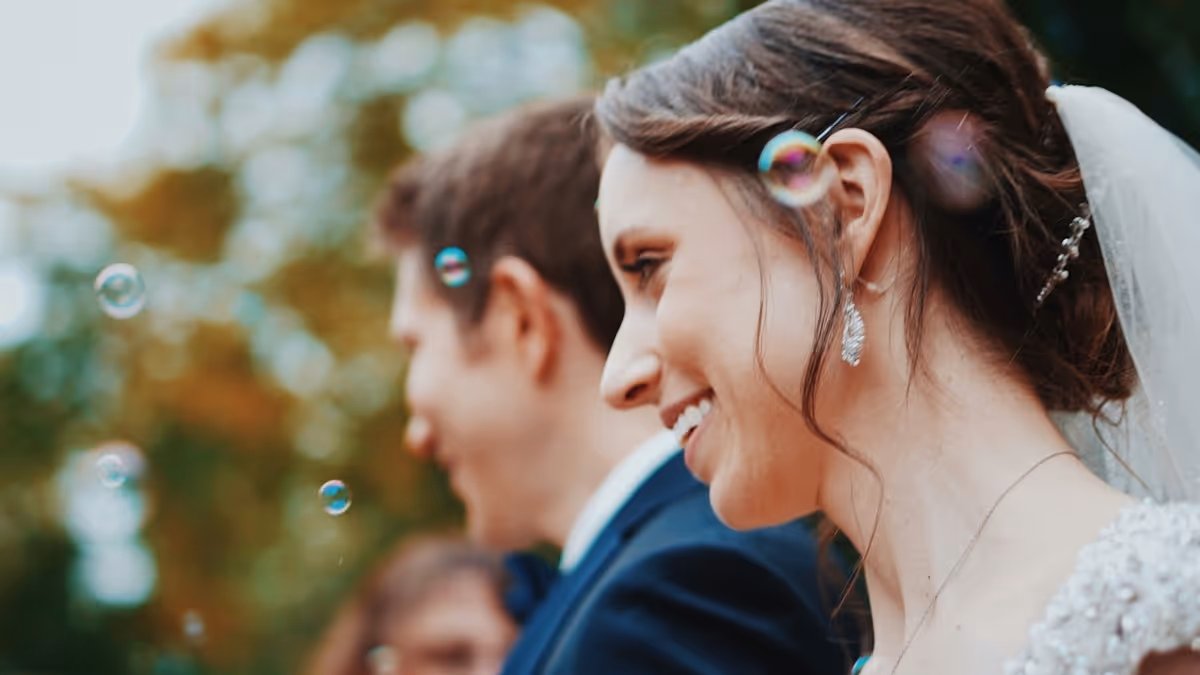 Novia y novio sonrientes durante una celebración rodeados de burbujas