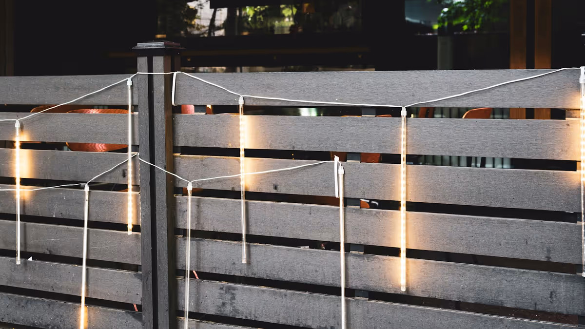 Luces de hilo iluminan valla de madera durante noche en terraza