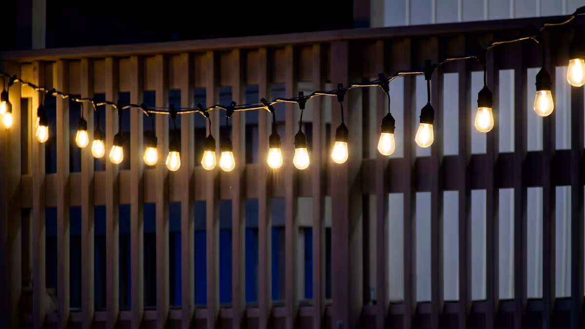 Luces de hilo iluminan barandilla de madera en terraza nocturna