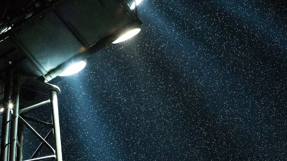 Luz blanca de reflectores de gran potencia sobre estructura metálica en una noche con nieve