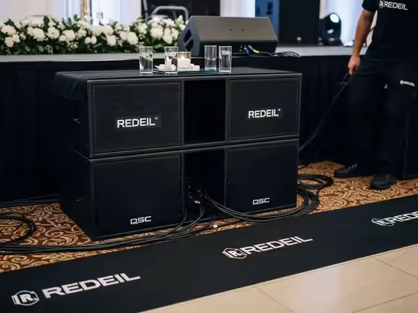 Stack de subwoofers QSC junto al escenario en evento