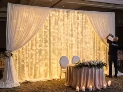 Mesa principal de boda con la pared cubierta de esquina a esquina por cortinas LED