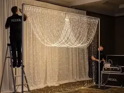 Técnico armando la estructura de truss de una cortina LED con escalera