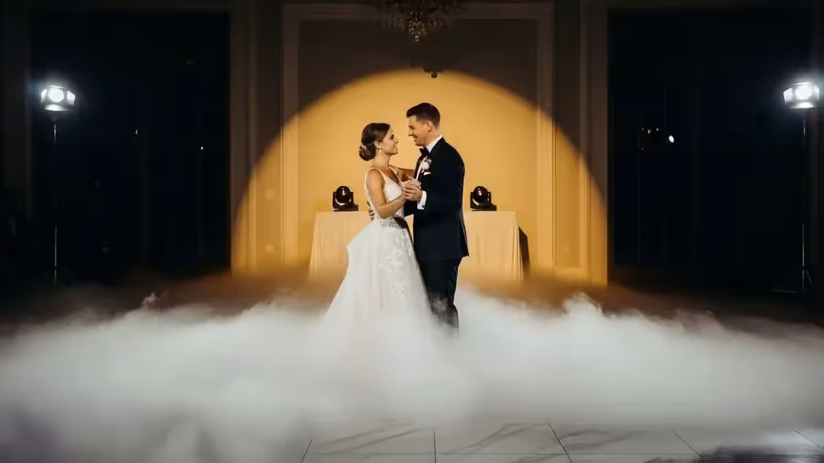 Pareja bailando sobre una capa de niebla en un salón de boda a media luz