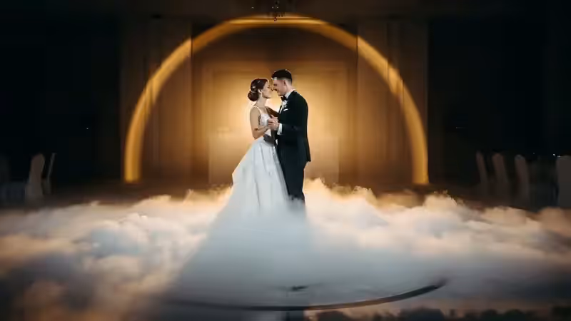 Novios bailando sobre niebla baja con el haz del seguidor encima en una boda de producción