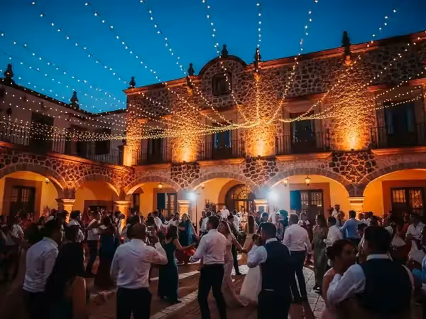 Parejas bailando afuera con la fachada de la hacienda en ámbar detrás