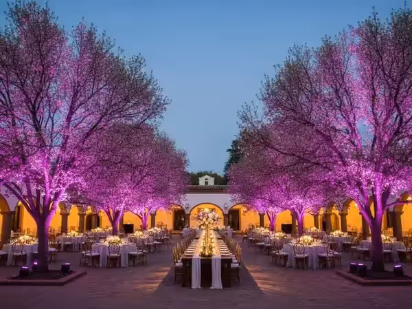 Mesa imperial en el jardín de una hacienda con los árboles del fondo en violeta