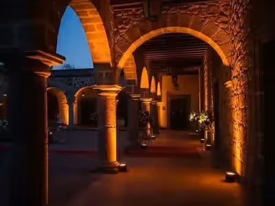 Corredor colonial de cantera en ámbar con arreglos florales entre los arcos