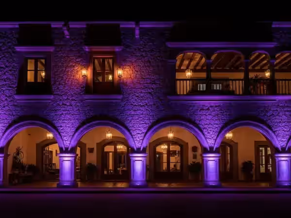 Arcos de piedra de hacienda mexicana iluminados en morado
