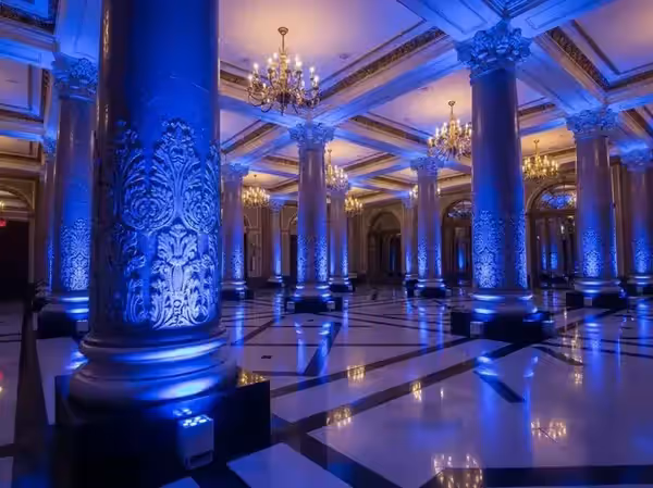 Salón de gala con piso de mármol y columnas encendidas en azul