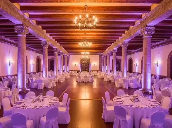 Salón de recepción con columnas en rosa y techo de vigas rústicas