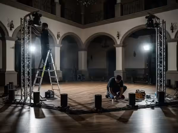 Montaje de iluminación en un salón grande con varios técnicos trabajando