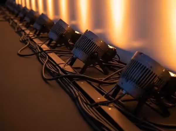 Línea de uplighters en ámbar colocados al pie de una superficie sin cableado a la vista