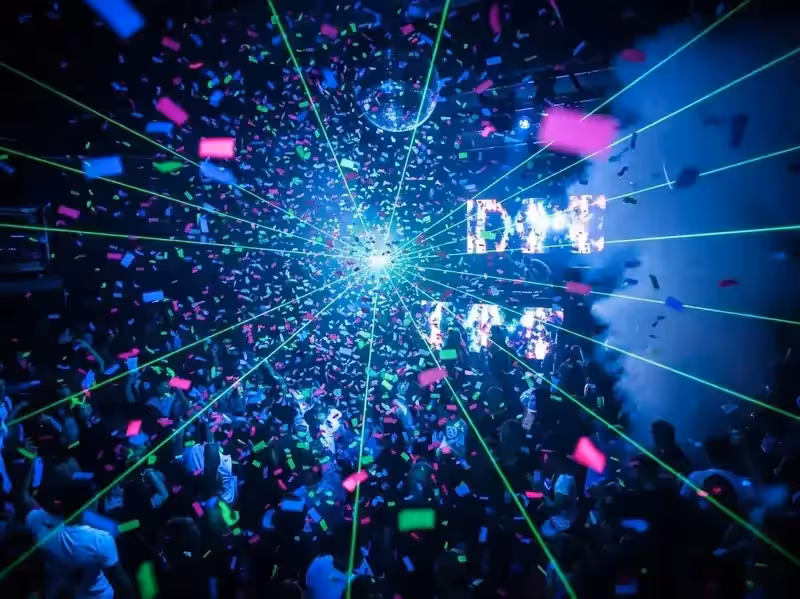 Confeti en discoteca con láser verde y bola de espejos