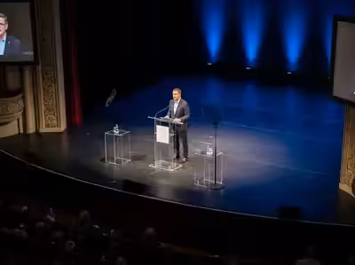 Podium en teatro con iluminación azul — referencia acabado oscuro