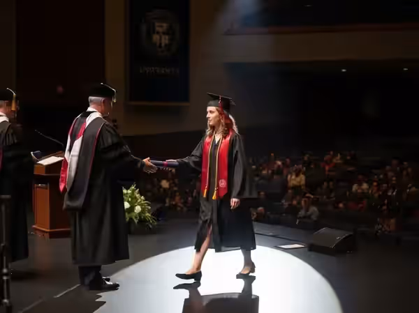Entrega de diploma iluminada con seguidor en un auditorio universitario
