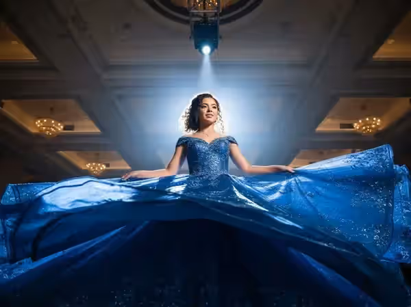 Quinceañera de vestido azul iluminada en un salón de candelabros altos