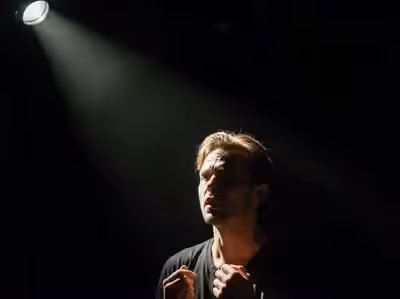 Actor en monólogo recortado del fondo negro por luz cruzada